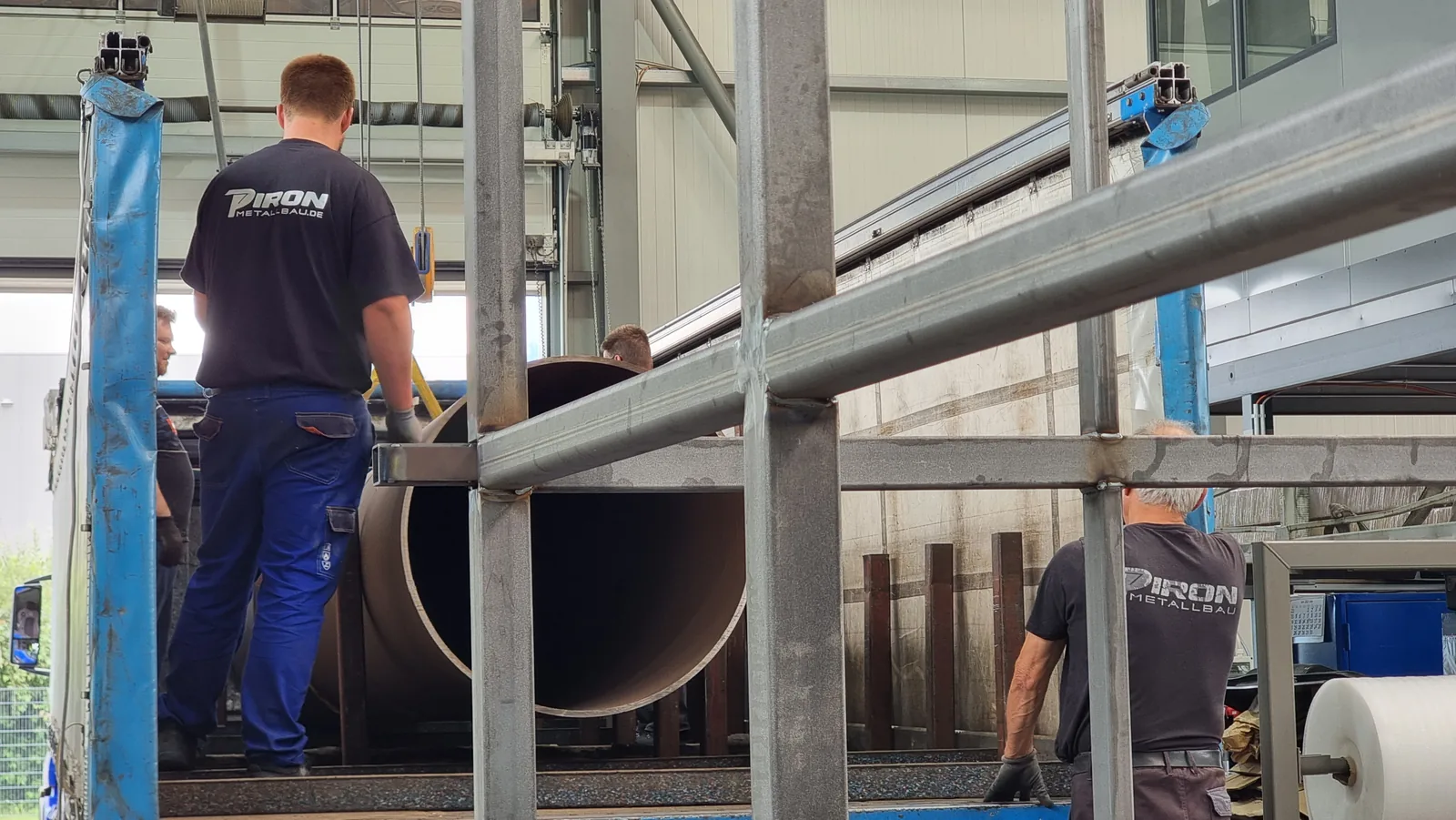 Mitarbeiter richten die Stahlsäule des Pylons in der Halle aus