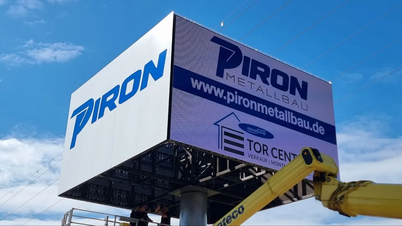 Der fertige Kubus mit PIRON-Logo und Tor-Center-Aufschrift, daneben der Kranarm