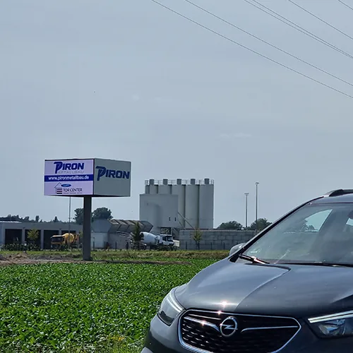 Die Wall über einem Feld, im Vordergrund die Motorhaube eines Autos