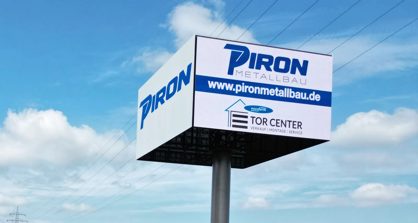 Die LED Wall mit PIRON-Logo an der Straße vor der Halle, von schräg unten